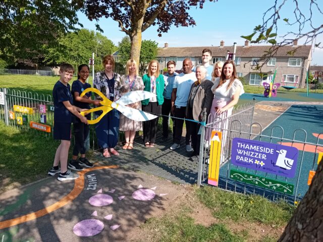 Collection of people around ribbon with oversized scissors