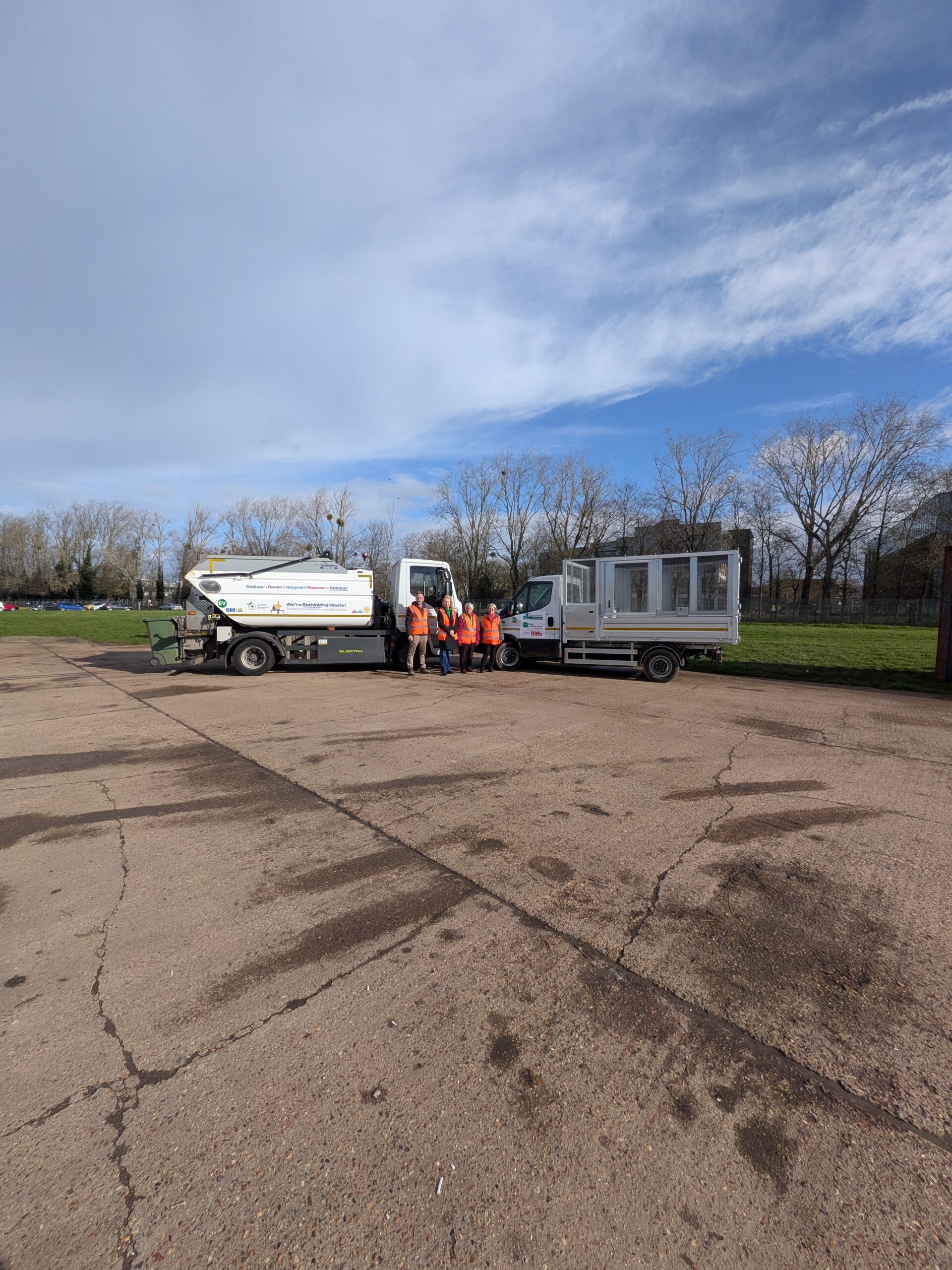 EV food waste truck and tipper truck in distance with councillors standing in front