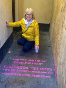 Cllr Helen Pighills stencilling messages in Abingdon about support for victims of domestic abuse