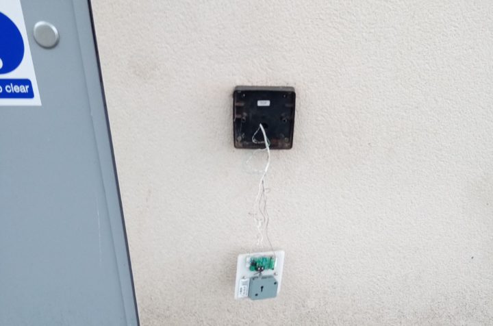 Damaged radar key hanging from socket on wall of public toilet