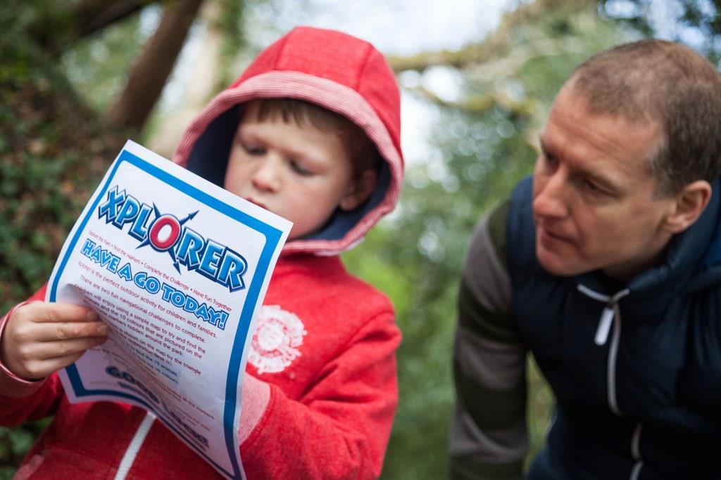 A man and a child looking a an Xplorer document out the woodlands