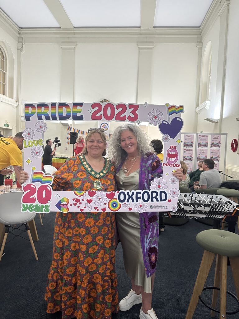 Two councillors pose in Pride frame