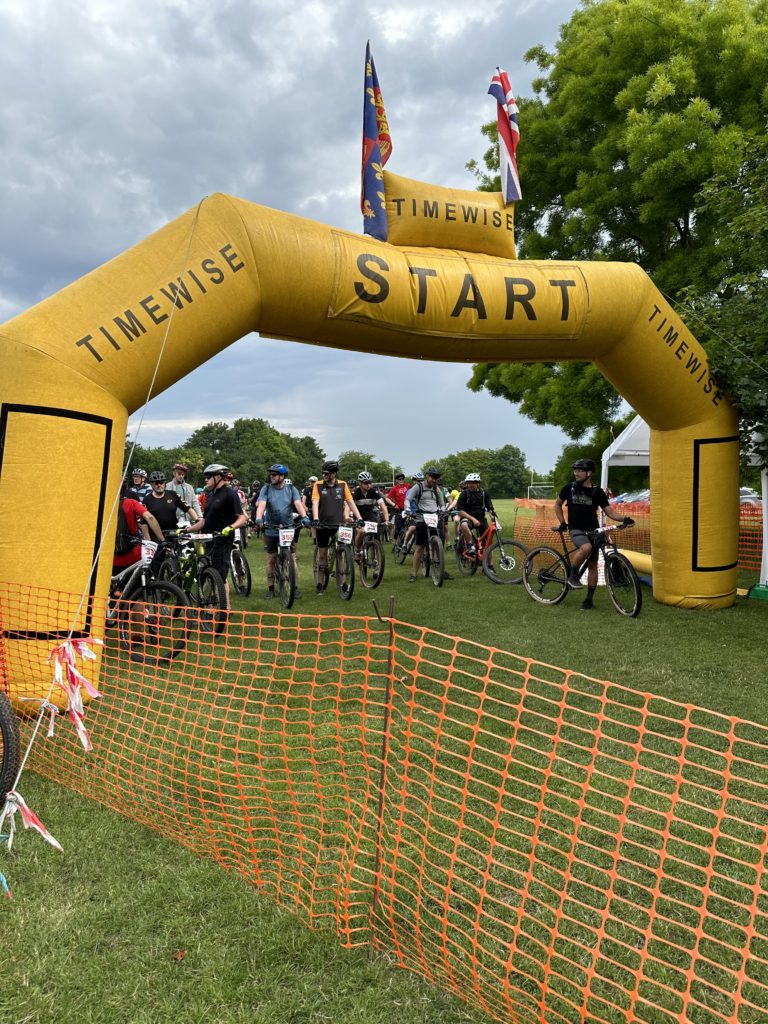 Cyclists at start line of cross country race under inflatable arch